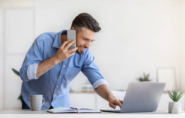 istock Corporate Communication. Businessman Talking On Cellphone And Using Laptop In Modern Office 1270378886