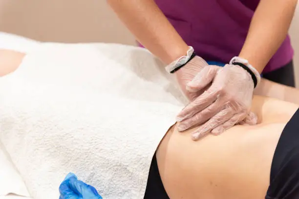 Detail of a female physiotherapist working with a patient during Coronavirus or Covid-19 pandemic.