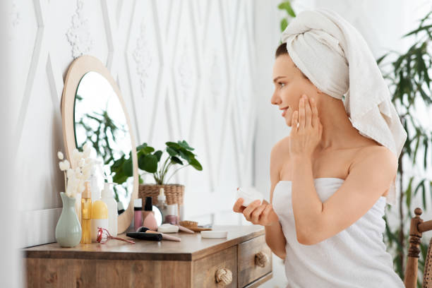 istock Pretty girl using face cream in front of mirror 1270382087