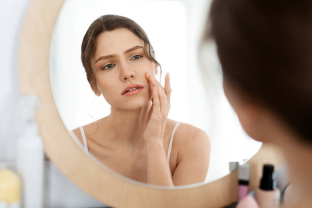 istock Upset young woman looking at mirror, checking her face skin 1270382177