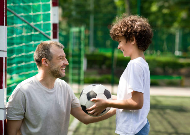 istock Happy father playing football on a grass with son 1270383055