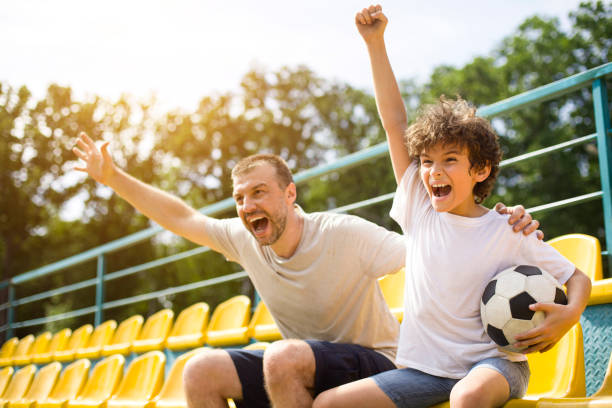 istock Dad and boy watching football game on stadium and cheering 1270383361