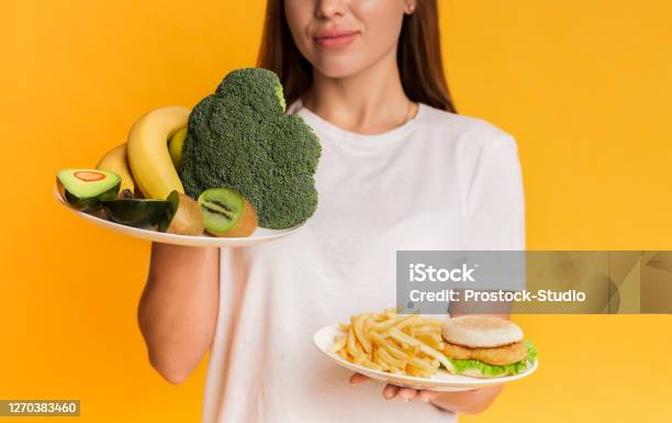 Girl Choosing Between Organic Fruits And Vegetables And Junk Food Stock Photo - Download Image Now