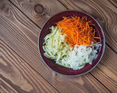 Chopped vines, carrots, onions and peppers for cooking in a brown enamel plate top view