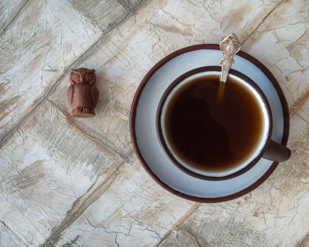 kaffee in einem braunen keramikbecher auf einer untertasse und einem euleförmigen schokoladenrohr - hot chocolate hot drink high section color image stock-fotos und bilder