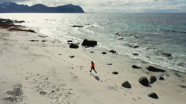 istock Aerial drone view: man running in Lofoten Islands 1270386240