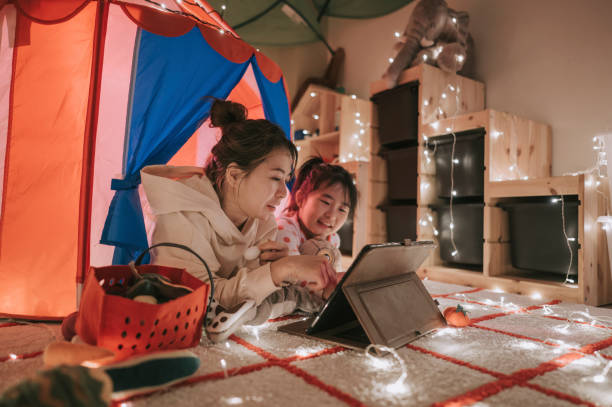 asiatico cinese bambino che gioca nella sala giochi nella tenda utilizzando tablet digitale sdraiato con la madre - video game family child playful foto e immagini stock