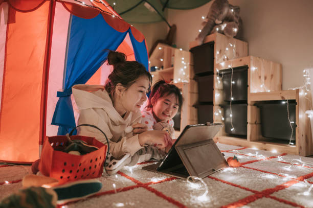 아시아 중국 아이 재생 에 이 놀이 방 에 텐트 사용 디지털 태블릿 누워 와 그녀의 어머니 - video game family child playful 뉴스 사진 이미지