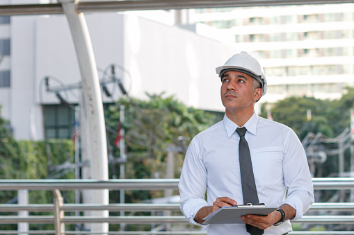 construction engineer standing holding agreement documents papers inspecting project development at the construction site