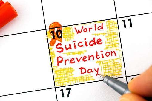 Woman fingers with pen writing reminder World Suicide Prevention Day in calendar. September 10.