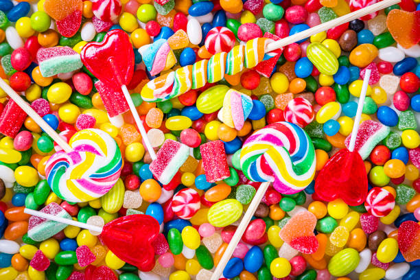 Assortment of multicolored candies, jelly beans and lollipops background stock photo
