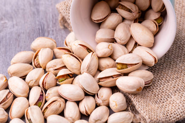 istock Pistachio nuts in a white ceramic bowl on a wooden table. 1270389789