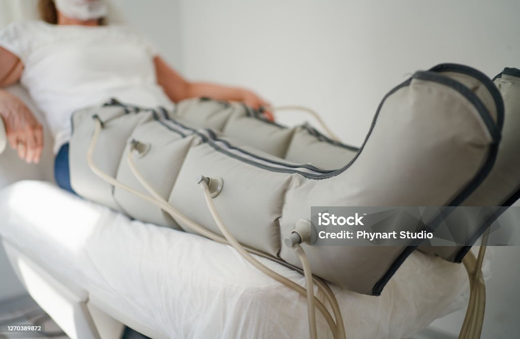 Pressure therapy Woman lying in massaging suit at the spa clinic for the treatment of pressure therapy procedure Lymphatic System Stock Photo