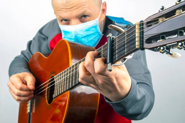 istock man in a medical mask plays the classical guitar on a white background. musical creativity. string musical instrument 1270392236