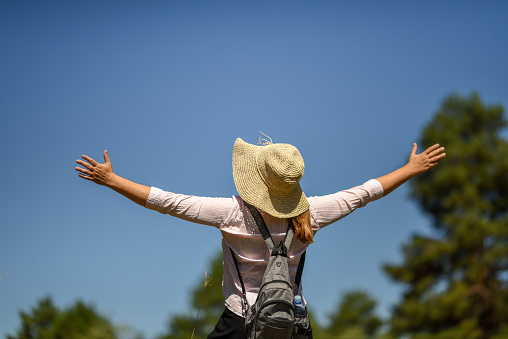 Woman feeling full of positive energy in the nature under the blue sky