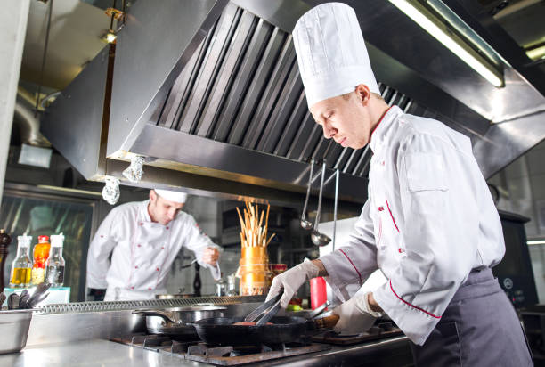 istock Chef in restaurant kitchen at stove with pan, cooking. 1270393623