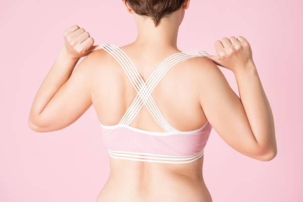 femme d’ajustement dans le soutien-gorge de sports sur le fond rose - undressing bra women rear view photos et images de collection