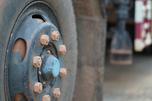Close-up at heavy truck or trailer vehicle 's wheel part (Selective focus at once bolt part). Industrial logistic and transportation photo.