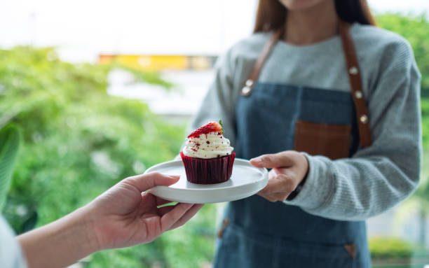 istock A waitress holding and serving red velvet cupcake to customer 1270395994