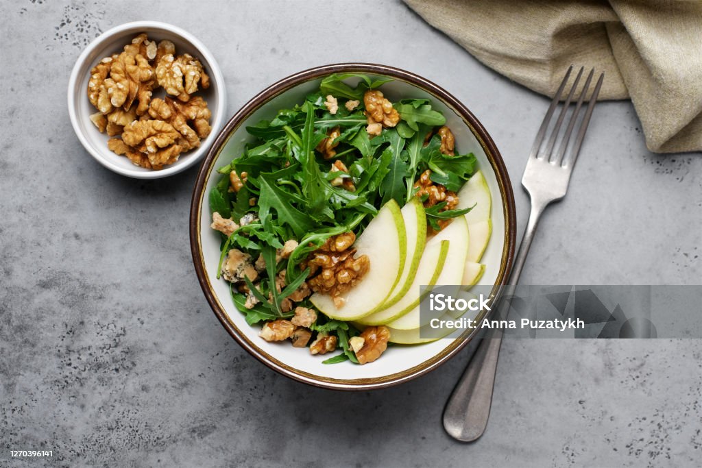 Fruit salad with pears, arugula, walnuts and Roquefort cheese Delicacy appetizer in bowl on gray background Salad Stock Photo