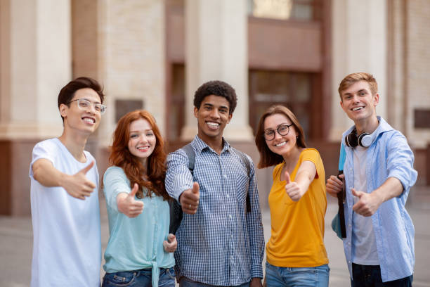 Diverse Students Gesturing Thumbs-Up Smiling To Camera Standing Outside Diverse Students Gesturing Thumbs-Up Smiling To Camera, Approving Their College Educational Program Standing Outside. Advice from Current Graduate Students stock pictures, royalty-free photos & images