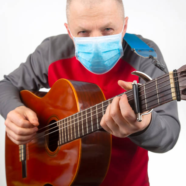 istock man in a medical mask plays the classical guitar on a white background. musical creativity. string musical instrument 1270396576