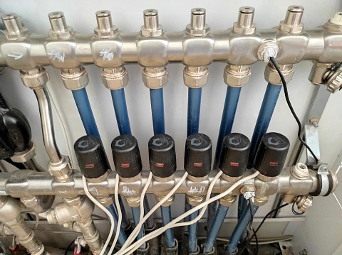 Distributor of central heating. Collector case with comb and taps on pipes of heating system connected to it. Pipes on Central Heating Distributor.