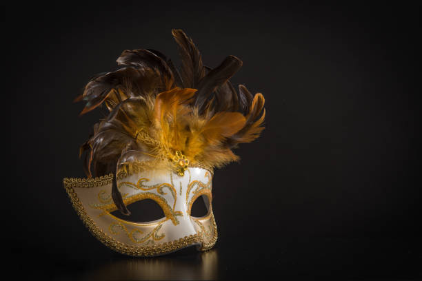 istock Pretty venician golden carnival mask with feathers isolated on a mysterious black background 1270400807