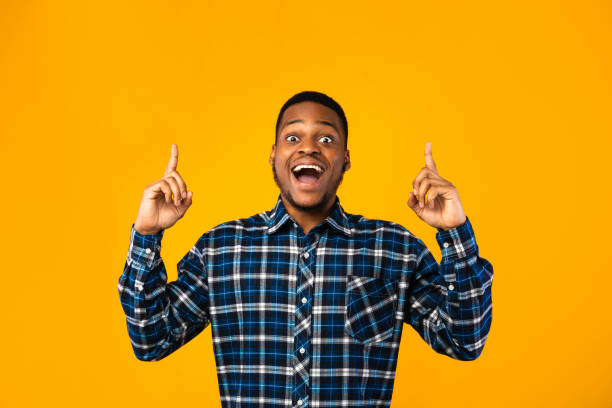 istock Excited African American Guy Posing Pointing Fingers Up, Yellow Background 1270402430