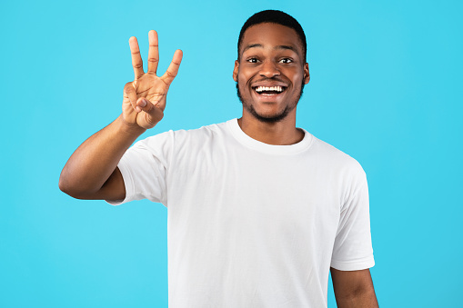 Number Three. African American Guy Showing Three Fingers Counting Standing Over Blue Background. Studio Background