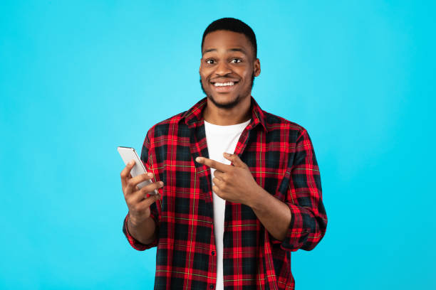 istock African Guy Pointing Finger At Smartphone Standing Over Blue Background 1270402844