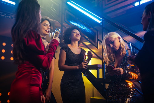 Cheerful young females drinking champagne and enjoying at nightclub