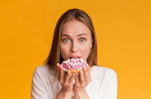 istock Young Woman Biting Tasty Donut, Posing Over Yellow Background In Studio 1270405235