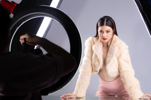 Asian Woman wear fashion fur and apply fashion make up. Photographer shoot 20s young woman with studio flash lighting