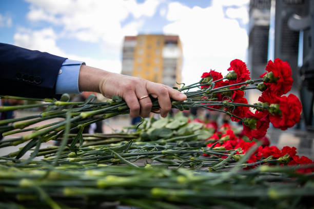 istock A hand puts red carnations on a granite gravestone. Memory of the dead 1270407768