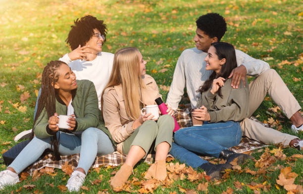 istock Young cheerful friends having picnic in forest, drinking coffee 1270407852
