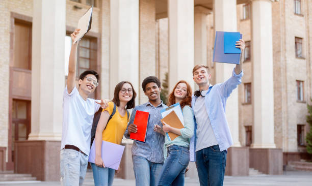istock Cheerful Diverse Students Posing Standing Outside University Building 1270409673