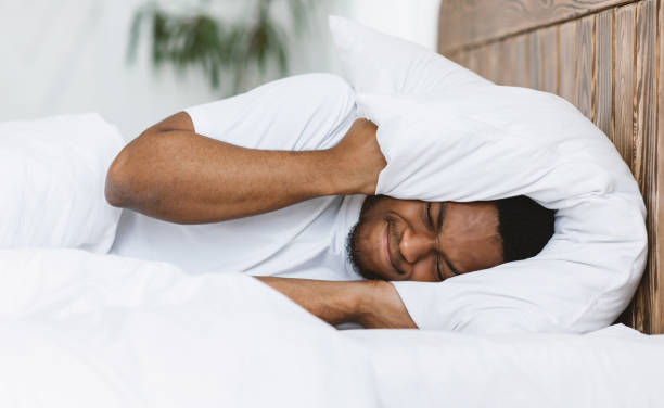istock Disturbed Man Covering Ears With Pillow Suffering From Insomnia Indoor 1270410971