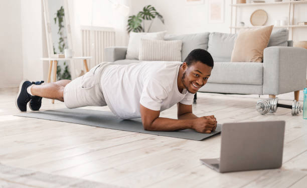 istock Black Man Exercising Doing Plank Exercise At Laptop Indoors 1270411020