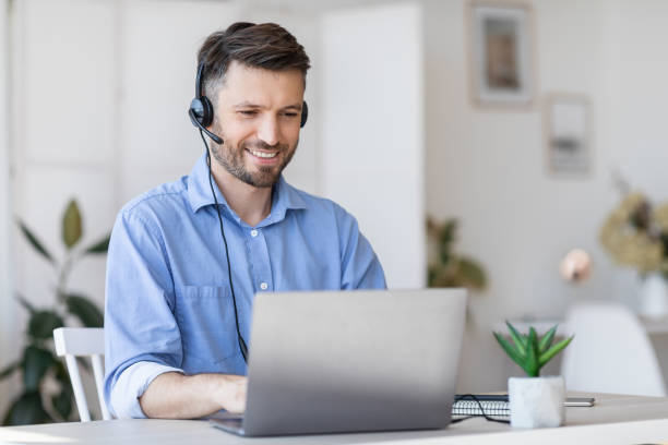 istock Call center operator at work. Male manager wearing headset and using laptop 1270411344