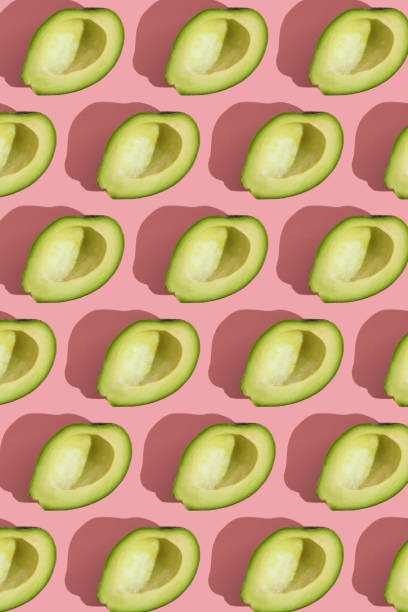 istock Trending style pattern of half seedless green avocado on pink background with hard light. Creative food texture. 1270411506