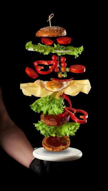 istock flying cheeseburger ingredients: meat cutlet, sesame bun, cheese, fried egg, tomato and green lettuce on a black background 1270412345