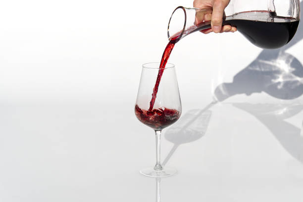 sommelier wylewa czerwone wino z dekanteru do kieliszka do wina na białym tle. - wine decanter elegance pouring zdjęcia i obrazy z banku zdjęć