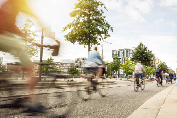 A group of moving cyclists in the city Motion blurred cyclists riding inside a city on a sunny day. urban lifestyle stock pictures, royalty-free photos & images