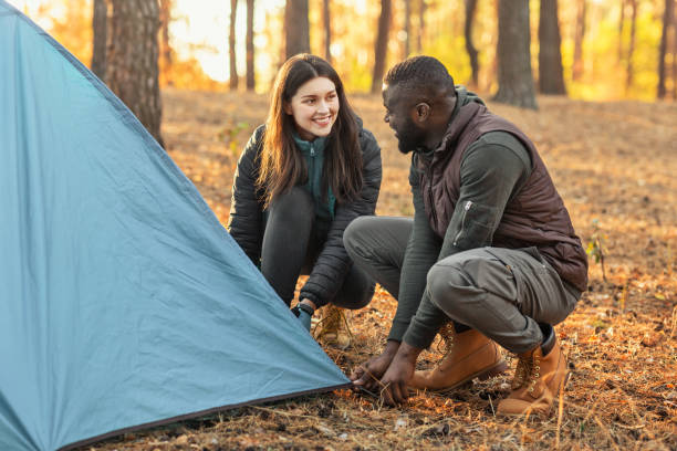 homme et femme faisant la tente ensemble, ayant la conversation - camping family tent couple photos et images de collection