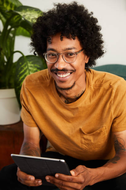 istock Smiling young man sitting at home using a digital tablet 1270413990