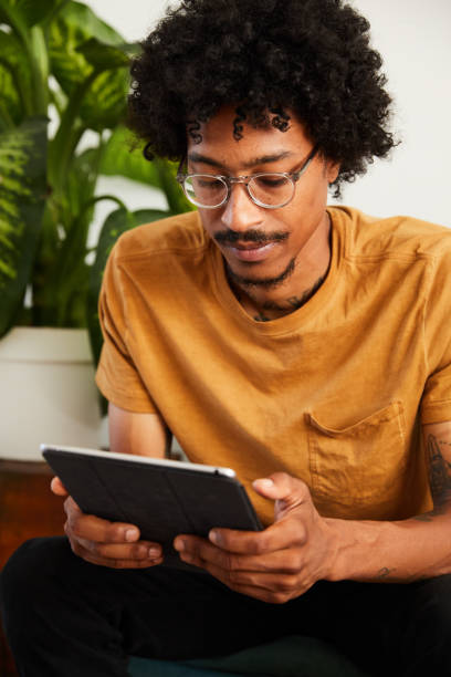 istock Young man relaxing at home using a tablet to browse the internet 1270414191