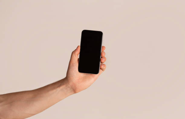 istock Male hand presenting smartphone with blank screen over light background, mockup for design 1270414337