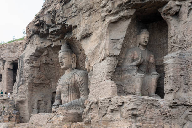 grande statue de bouddha assise et bouddha plus petit assis à les grottes de yungang - datong photos et images de collection