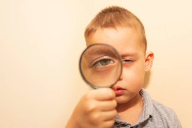 istock a child looks through a magnifying glass 1270415763